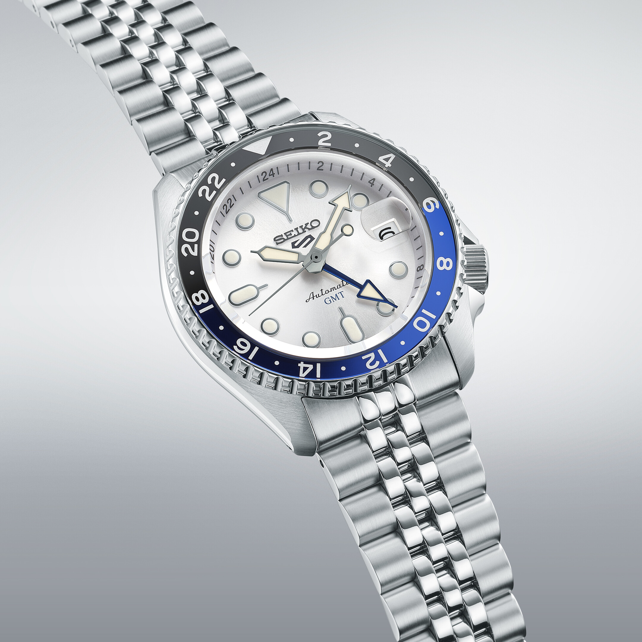 Silbernes Automatik-GMT-Armbanduhr mit weißem Zifferblatt und blau-schwarzer Lünette im Detail