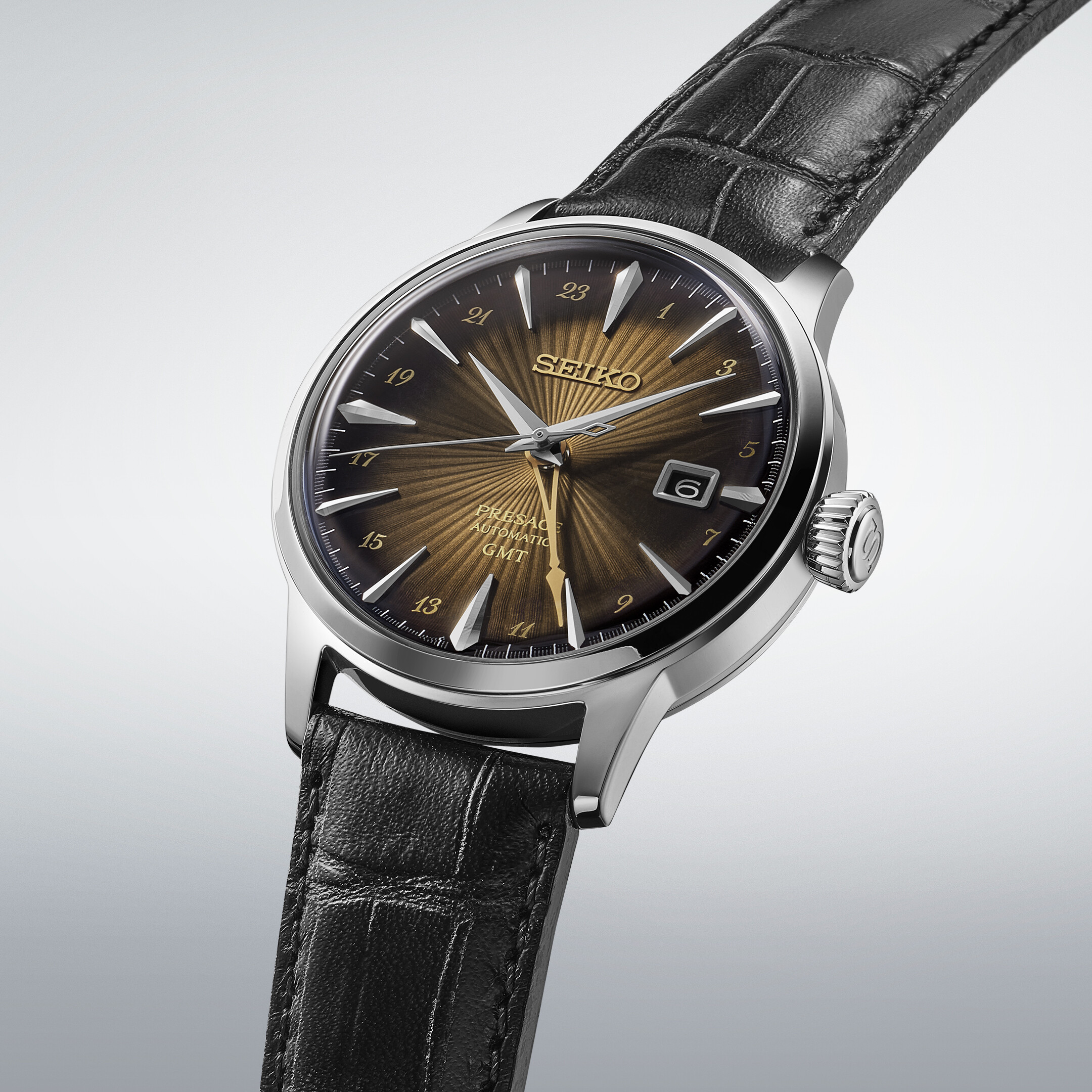 Eine Armbanduhr mit einem braun-goldenen Zifferblatt mit Sonnenschliff und einem schwarzen Lederarmband.