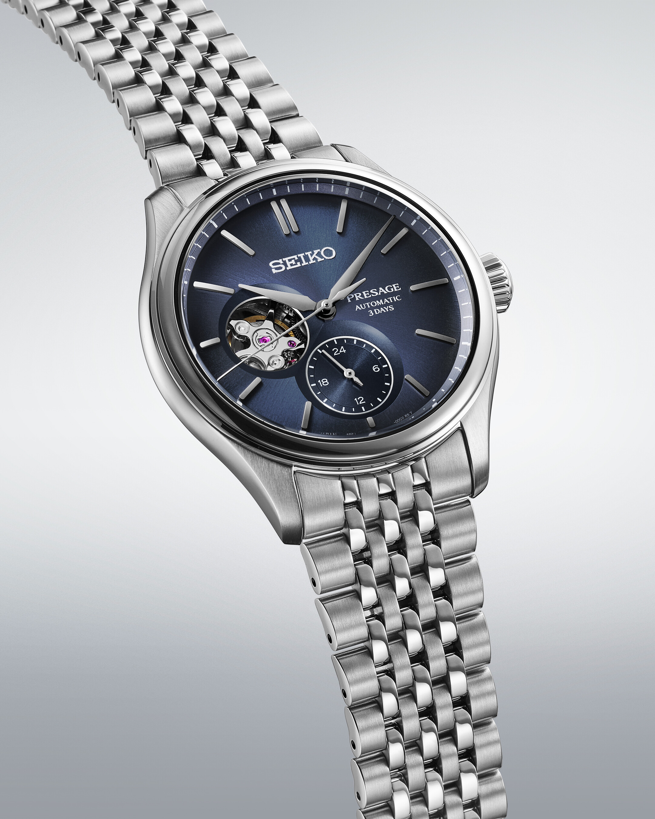 Eine Automatikuhr mit einem blauen Zifferblatt mit Sichtfenster und einem silbernen Armband.