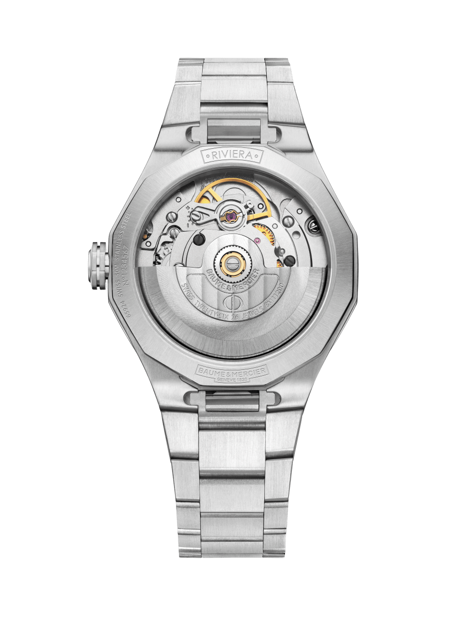 Rückseite einer silbernen Armbanduhr mit sichtbarem Uhrwerk und poliertem Metallarmband. Auf dem Zifferblatt sind die Worte "RIVIERA" und "BAUME & MERCIER" zu sehen.