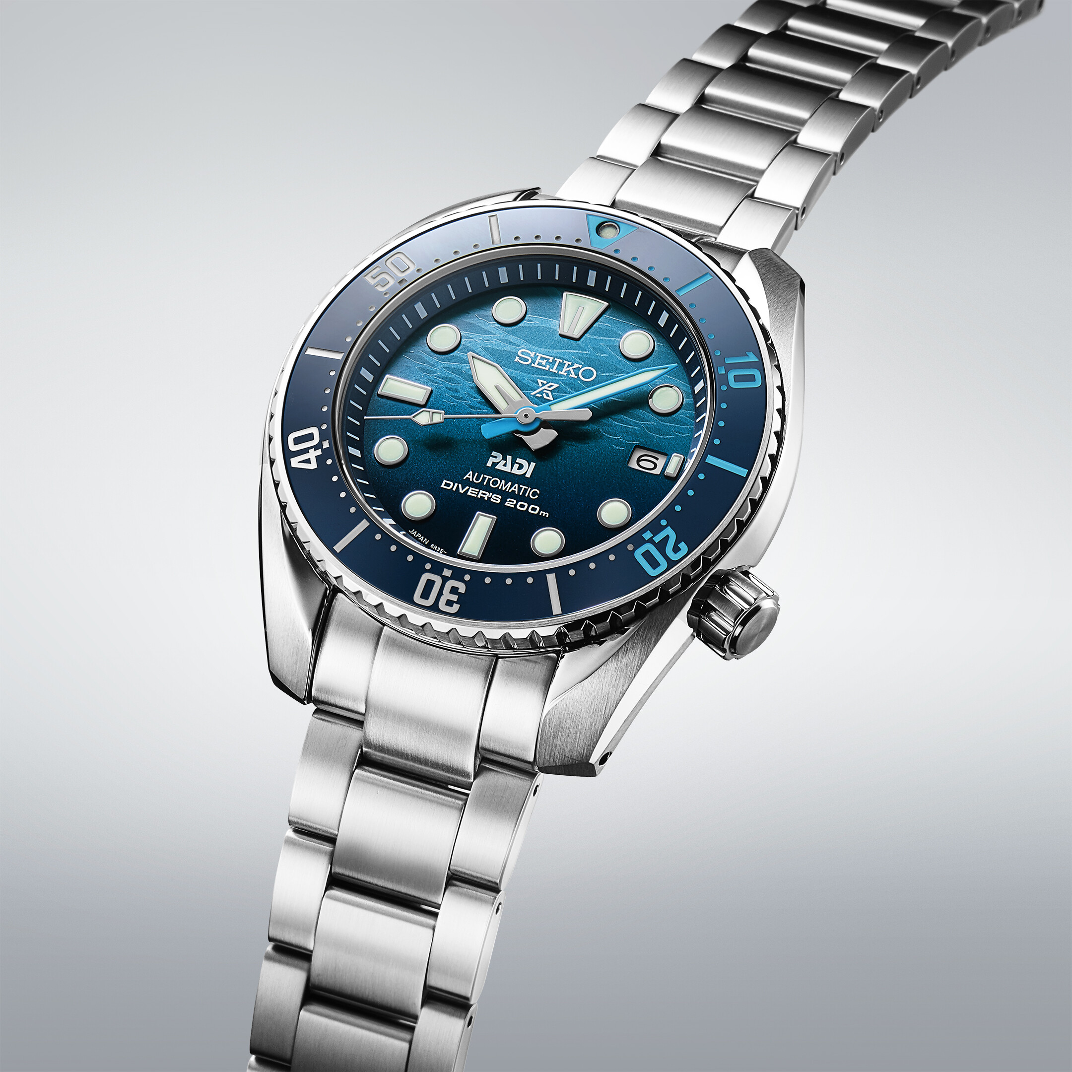 Eine silberne Armbanduhr mit blauem Zifferblatt mit Wellenmuster und silberner Lünette.