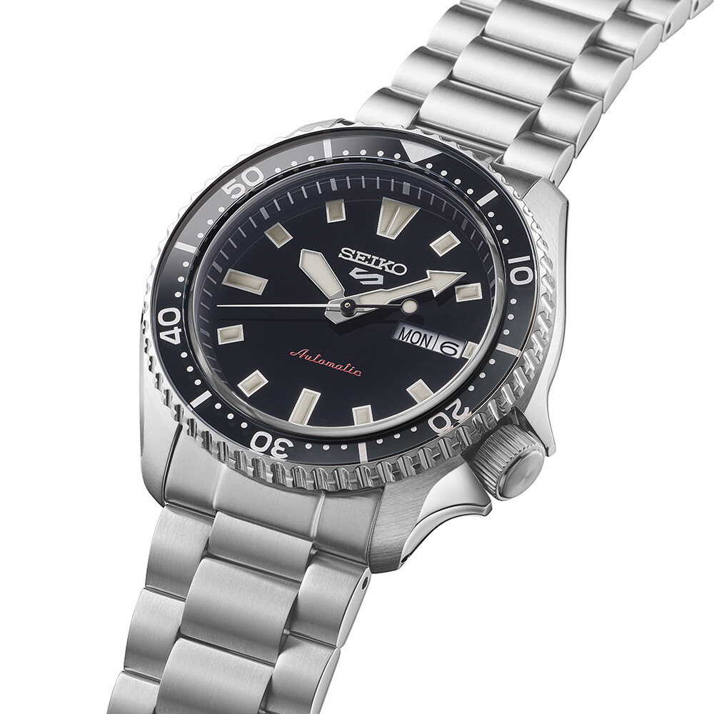 Eine silberne Armbanduhr mit schwarzem Zifferblatt und leuchtenden Zeigern und Markierungen.