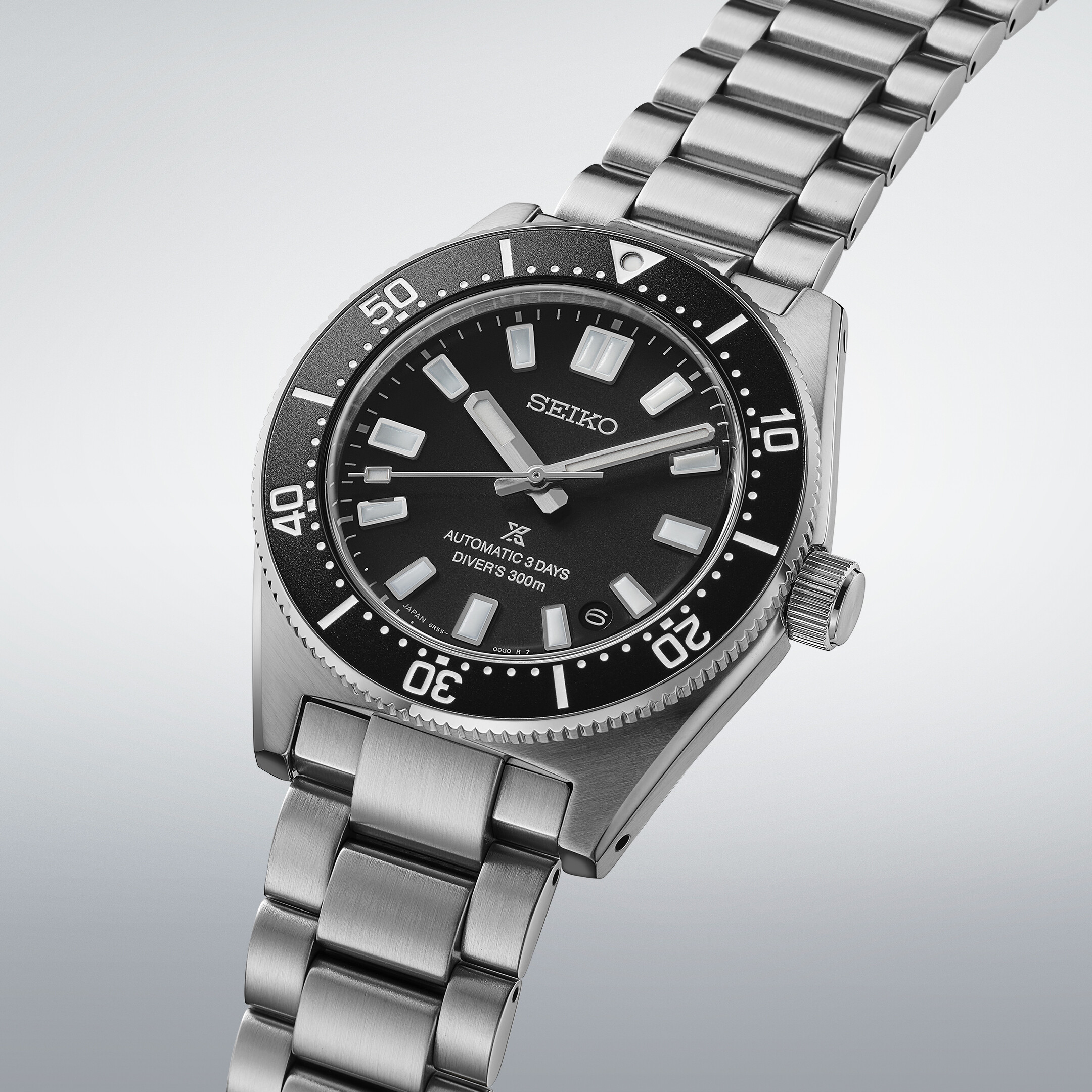 Eine silberne Armbanduhr mit schwarzem Zifferblatt und silbernem Armband. Sie hat eine drehbare Lünette mit weißen Markierungen.