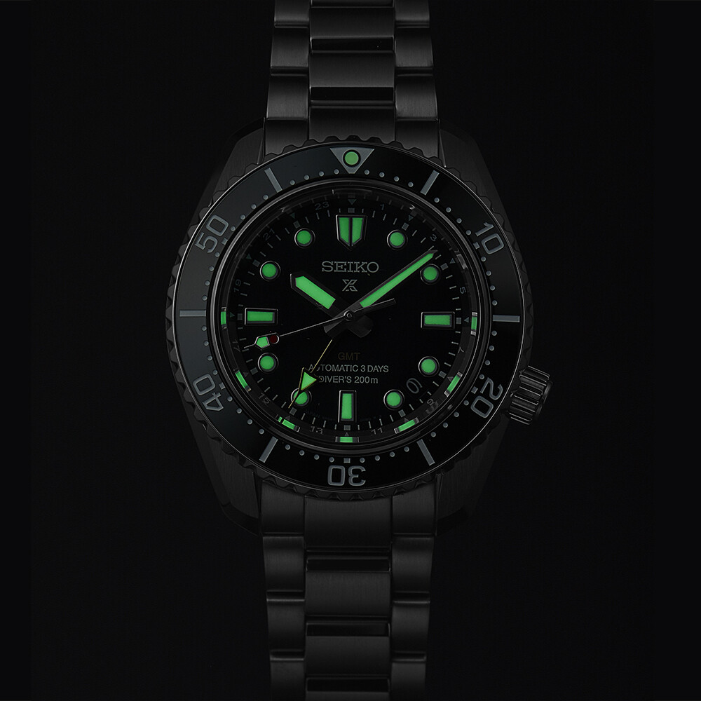 Schwarze Herrenuhr mit leuchtgrünen Zeigern und Indizes auf schwarzem Zifferblatt.
