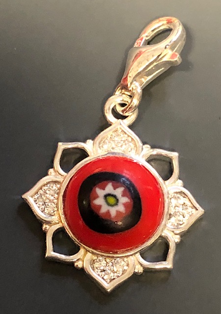 Ein roter Glas-Anhänger in Form einer Lotusblüte mit einem Muster und Glitzersteinen, Thomas Sabo.