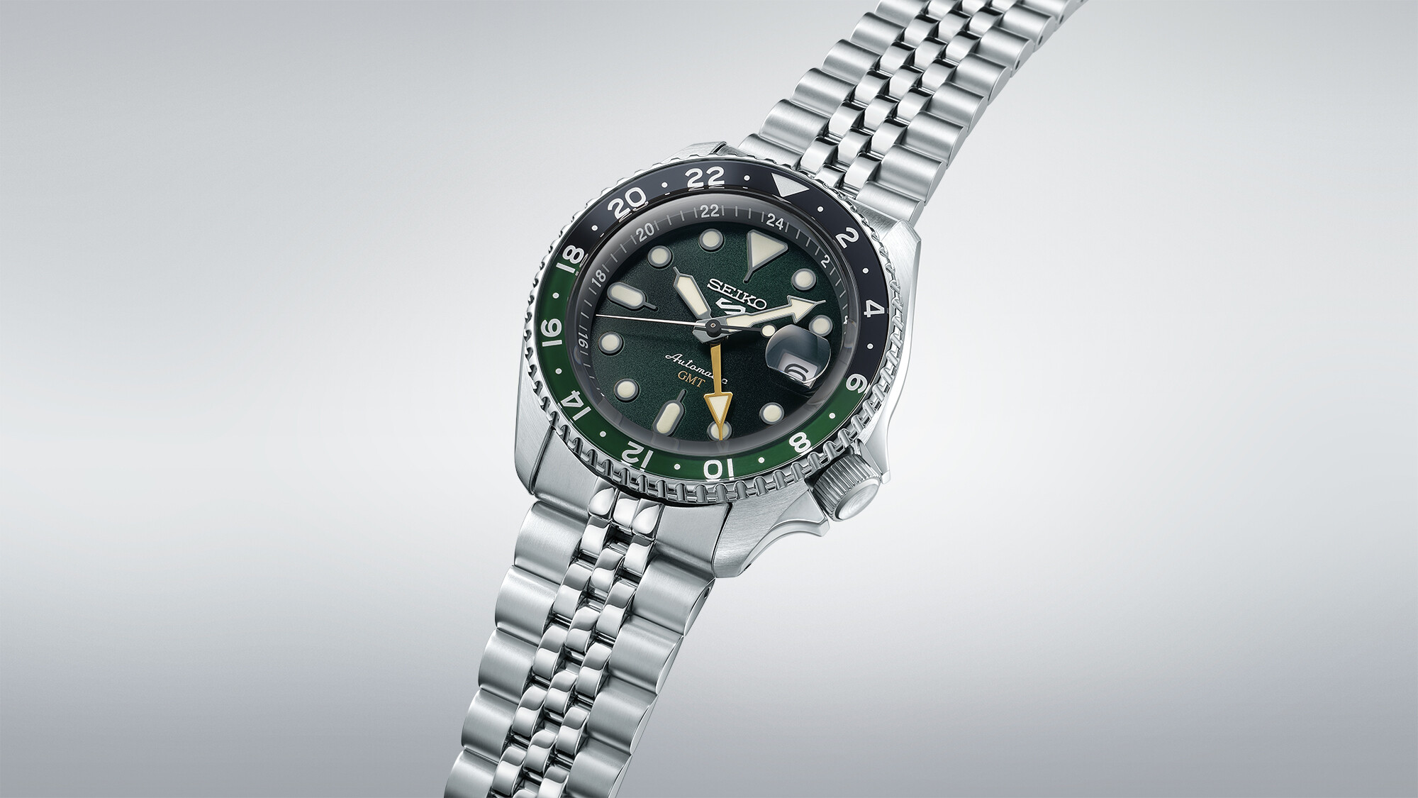 Eine silberne Armbanduhr mit einem dunkelgrünen Zifferblatt und einer schwarzen/grünen Lünette.