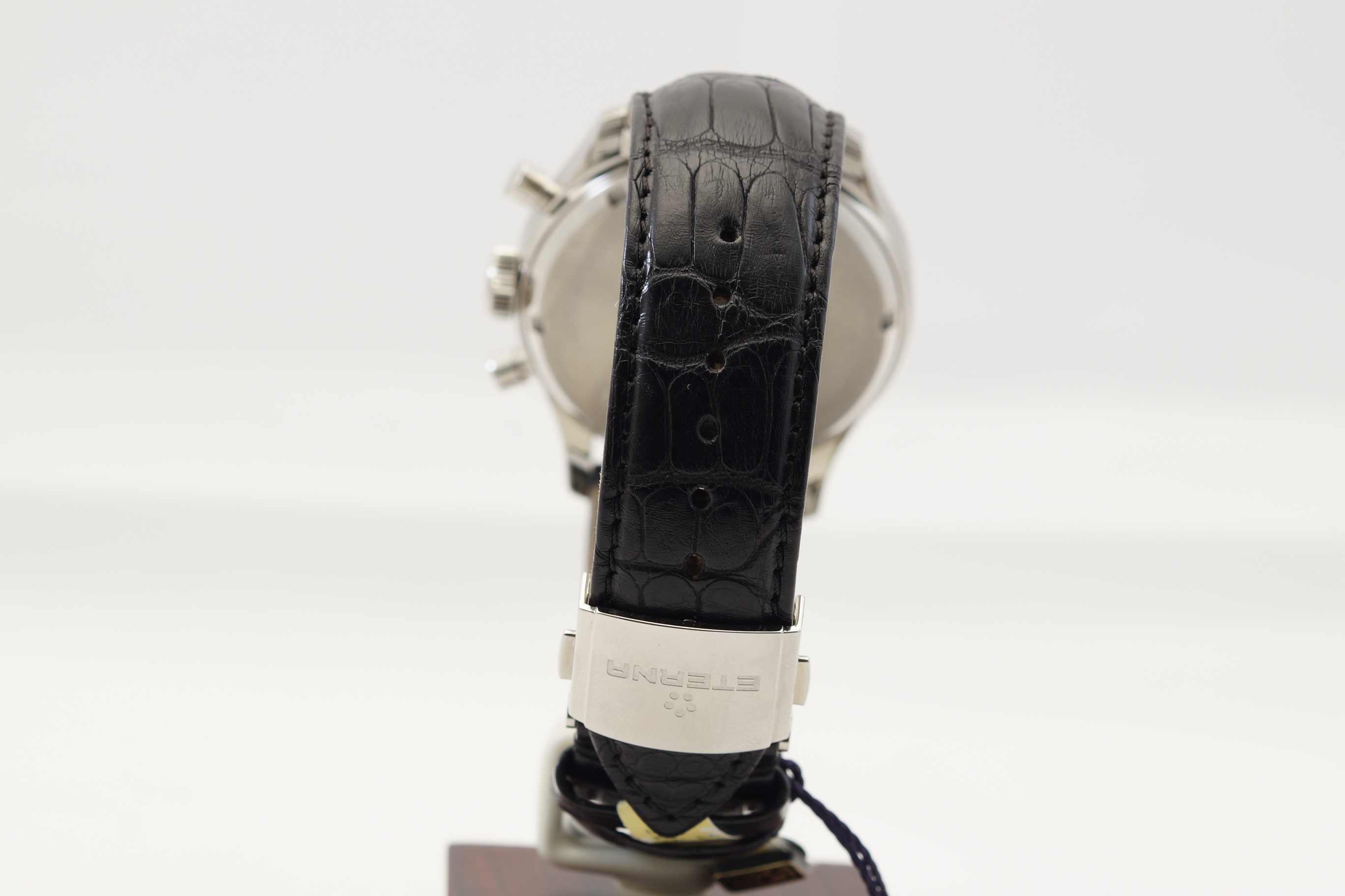 Ein schwarzes Lederarmband mit Krokodilprägung an einer silbernen Uhr, mit einem silbernen Verschluss.