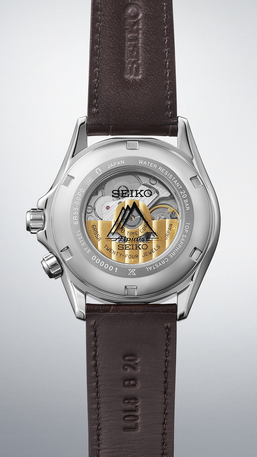 Ein silbernes Uhrengehäuse mit einem dunkelbraunen Lederarmband. Die Rückseite der Uhr zeigt ein durchsichtiges Gehäuse mit mechanischen Komponenten.