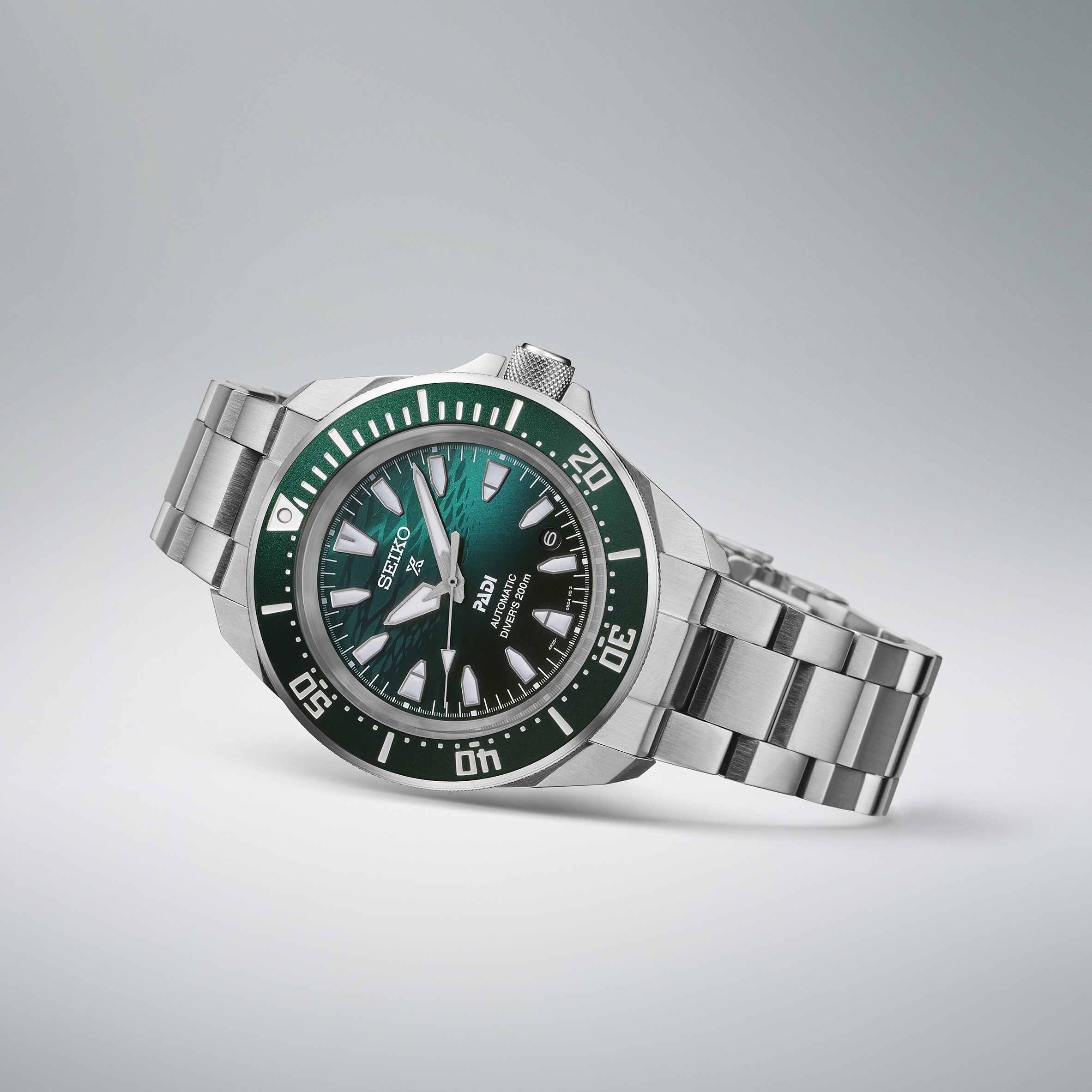 Eine automatische Taucheruhr mit einem dunkelgrünen Zifferblatt und silbernem Armband.