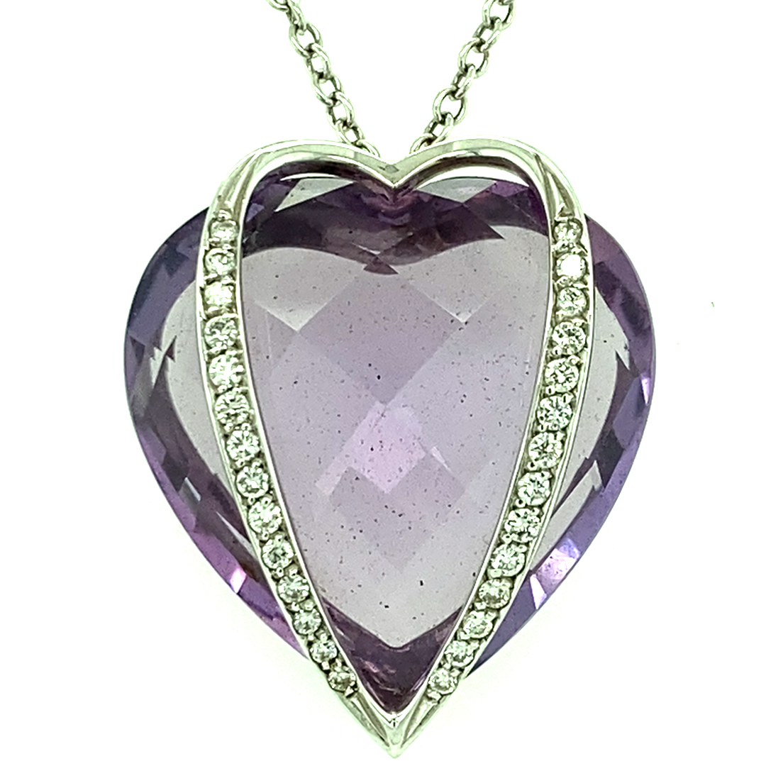 Ein Lazzaro Anhänger in Herzform mit einem facettierten, lila Amethyst und einer Reihe von kleinen, funkelnden Brillanten an einer silbernen Kette.