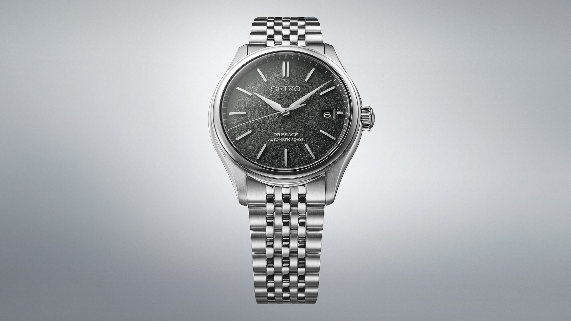 Eine silberne Herrenuhr mit einem dunklen, strukturierten Zifferblatt und silbernem Armband.