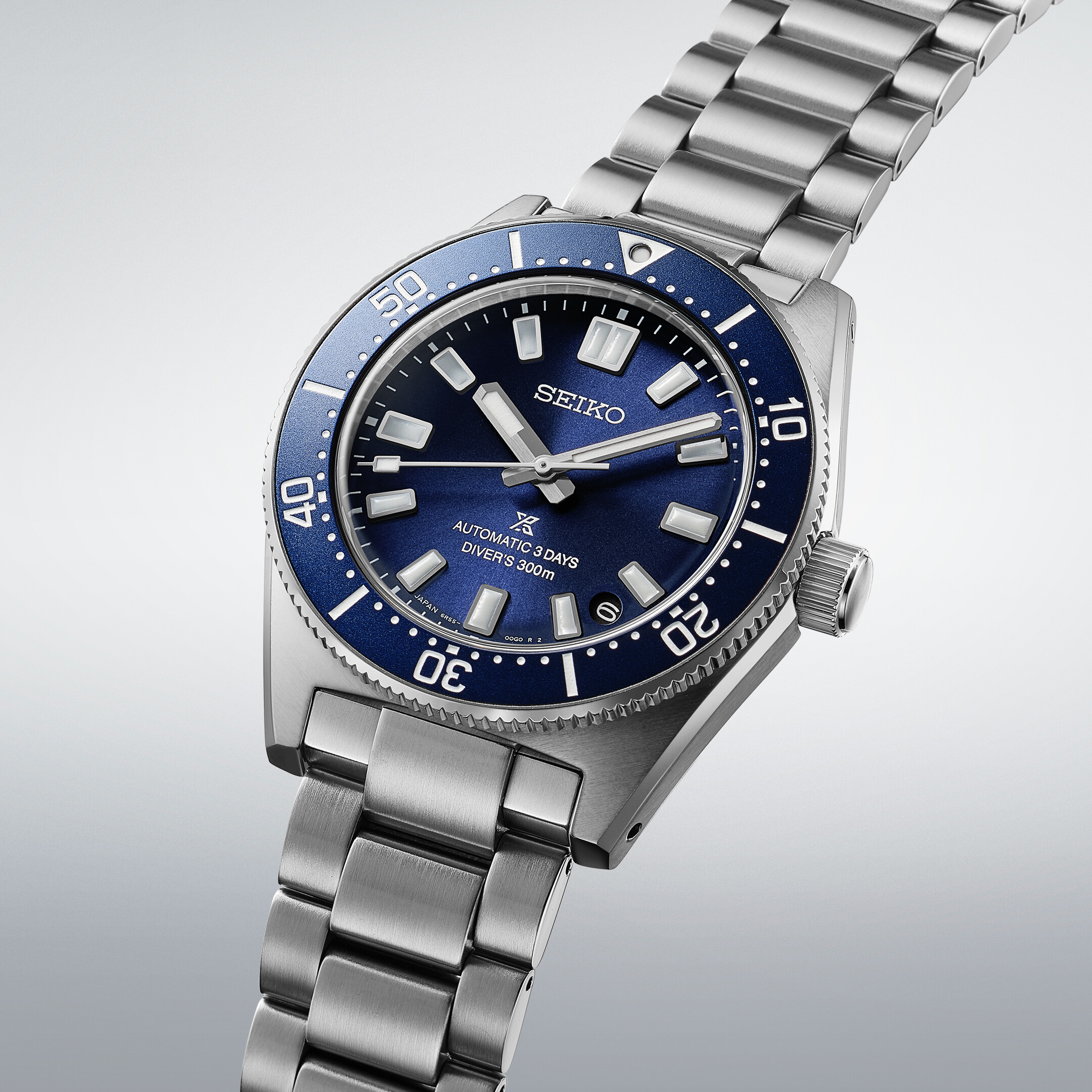Eine silberne Taucheruhr mit einem tiefblauen Zifferblatt und einer blauen Lünette mit weißen Markierungen.