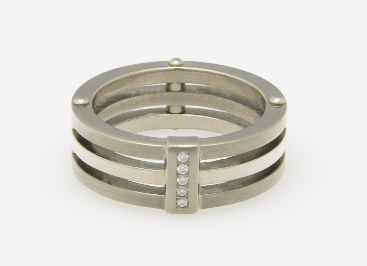 Ein silberfarbener Ring mit vier Bändern und drei Diamanten in einem rechteckigen Einsatz.