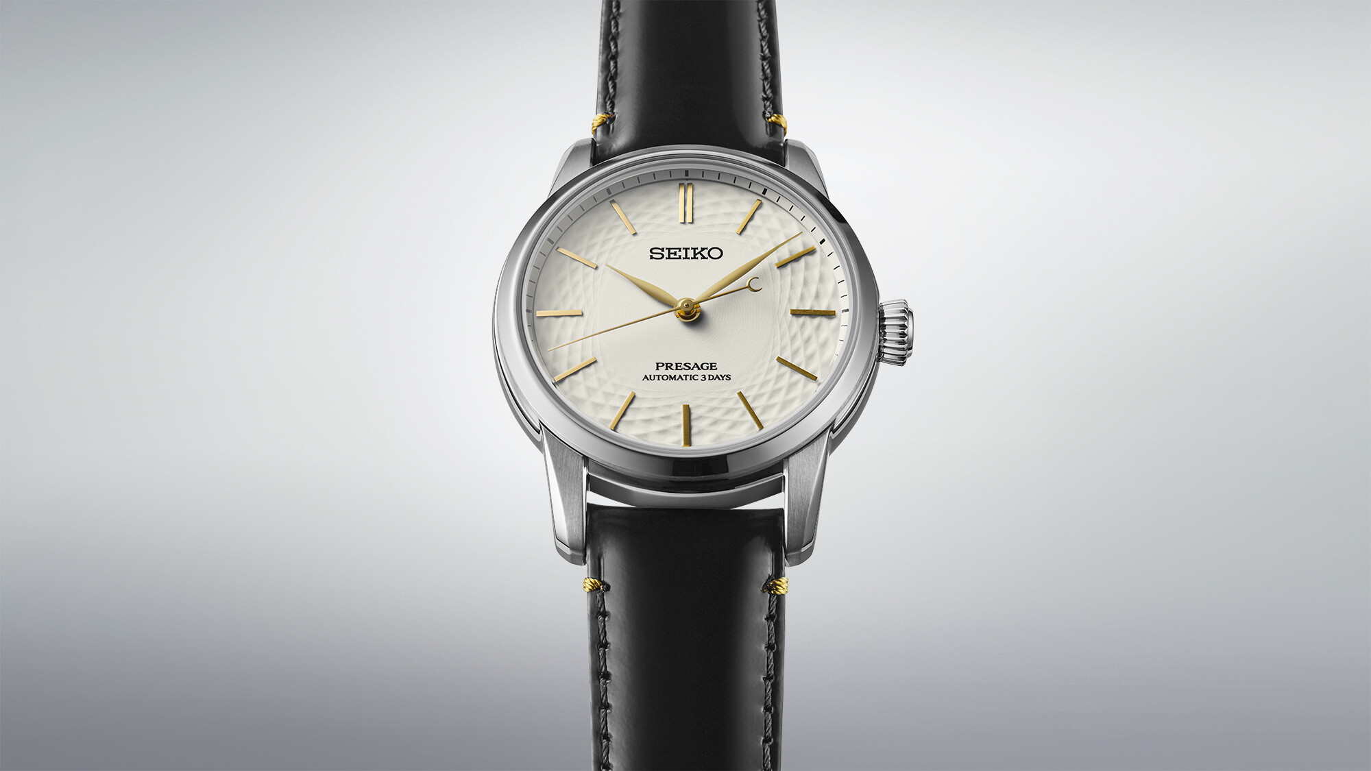 Eine silberne Uhr mit weißem Zifferblatt und goldenen Zeigern und Markierungen mit einem strukturierten Muster.