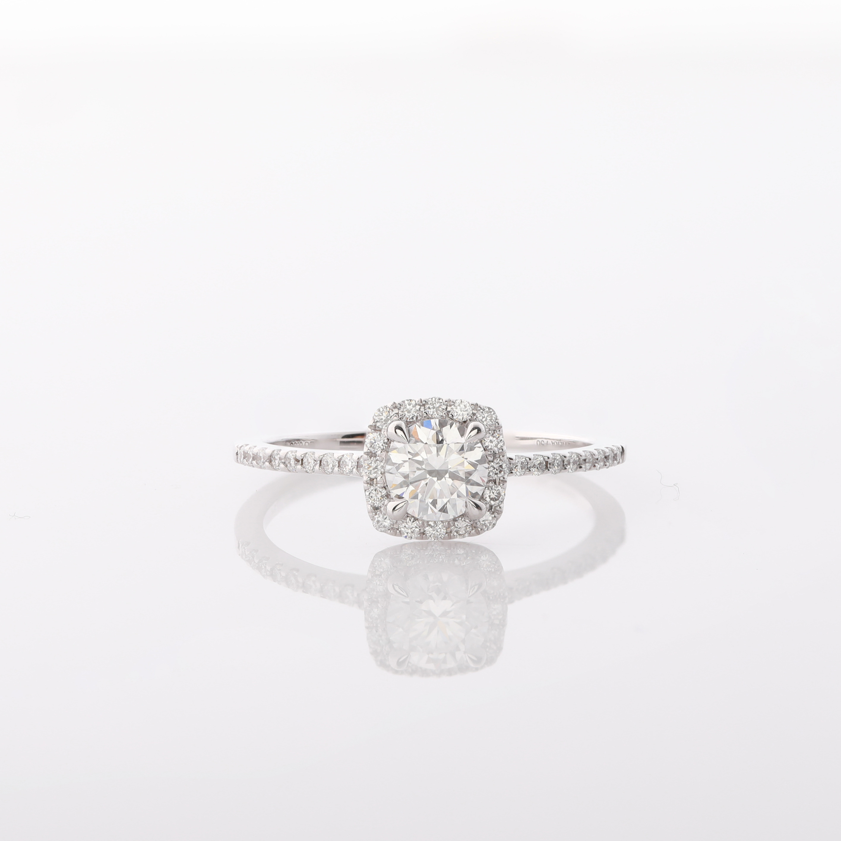 Ein glänzender Ring mit einem quadratisch gefassten, strahlenden Diamanten und kleineren Steinen am Band.