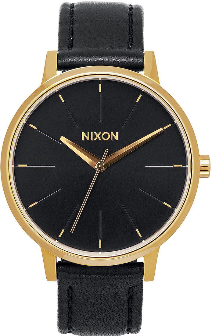 Die Nixon Kensington Uhr zeigt ein schwarzes Zifferblatt mit goldenen Indizes und Zeigern sowie ein goldenes Gehäuse und ein schwarzes Armband.