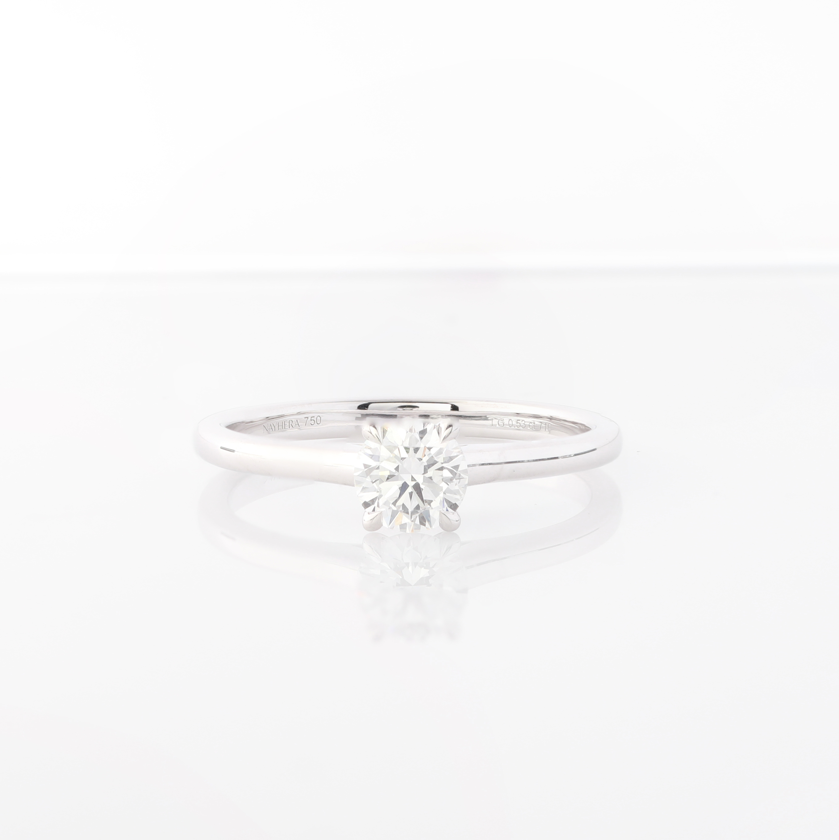 Ein silberner Ring mit einem runden, facettierten Diamanten in der Mitte.