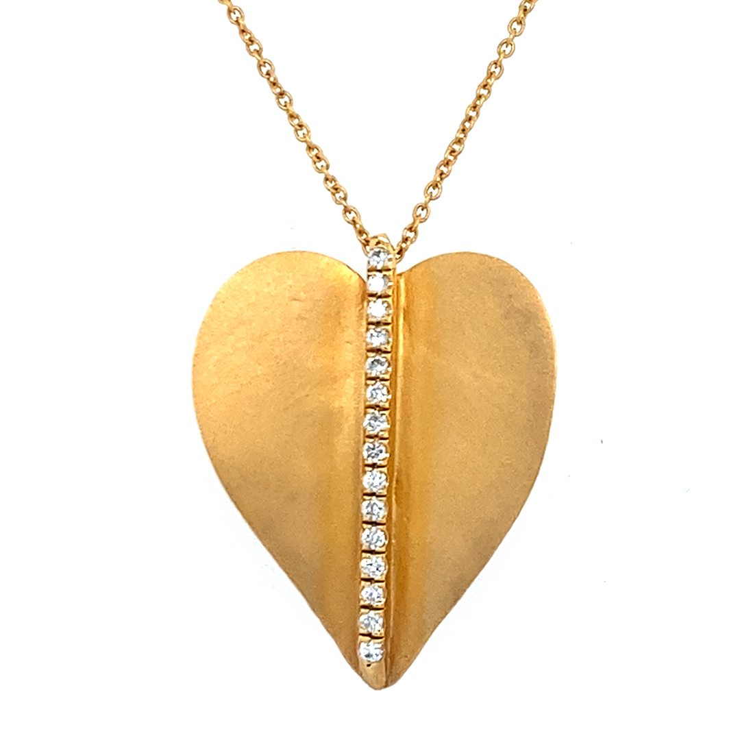 Eine goldene Kette trägt einen markanten Herzanhänger, der in der Mitte von einer Reihe funkelnder Schmucksteine geschmückt wird.