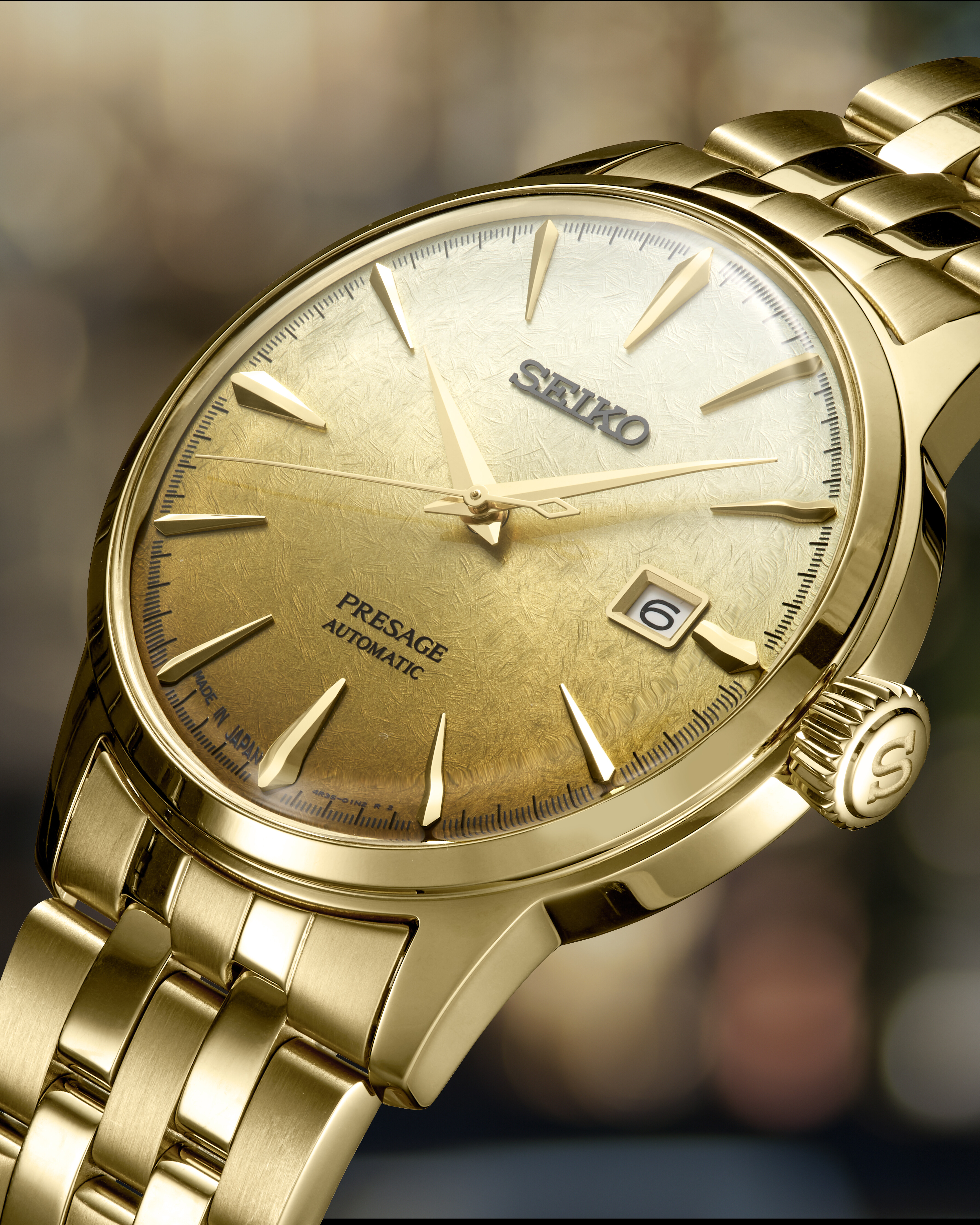 Eine goldene Armbanduhr mit einem strukturierten, goldenen Zifferblatt und einem Datumsfenster.