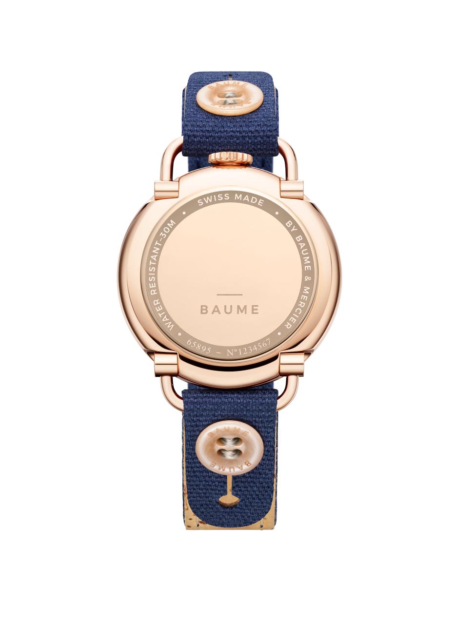 Eine roséfarbene Uhr mit einem dunkelblauen Stoffarmband, das mit einem runden Knopf befestigt ist.