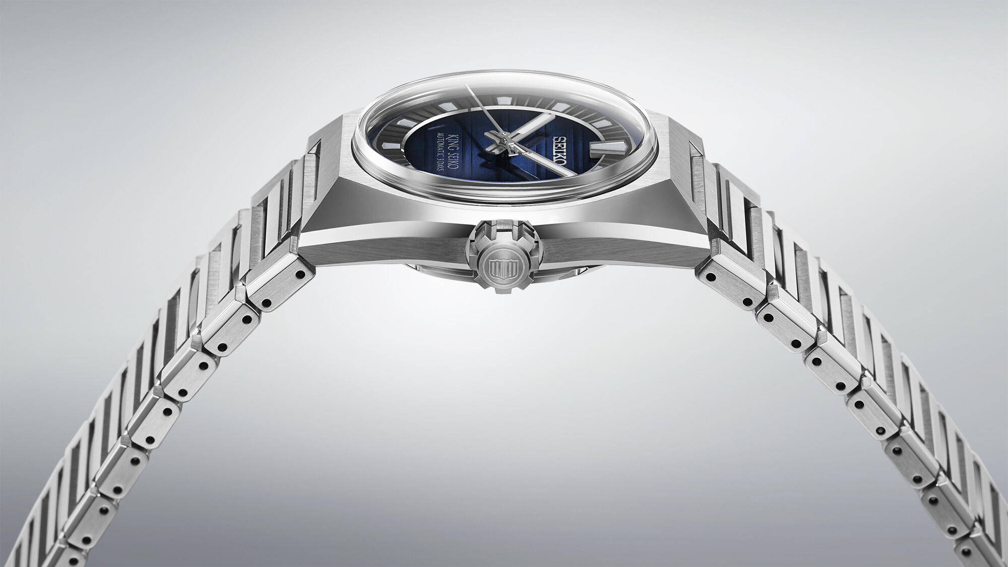 Silbernes Herrenarmbanduhr mit blauem Zifferblatt und silbernen Zeigern auf einem hellgrauen Hintergrund.