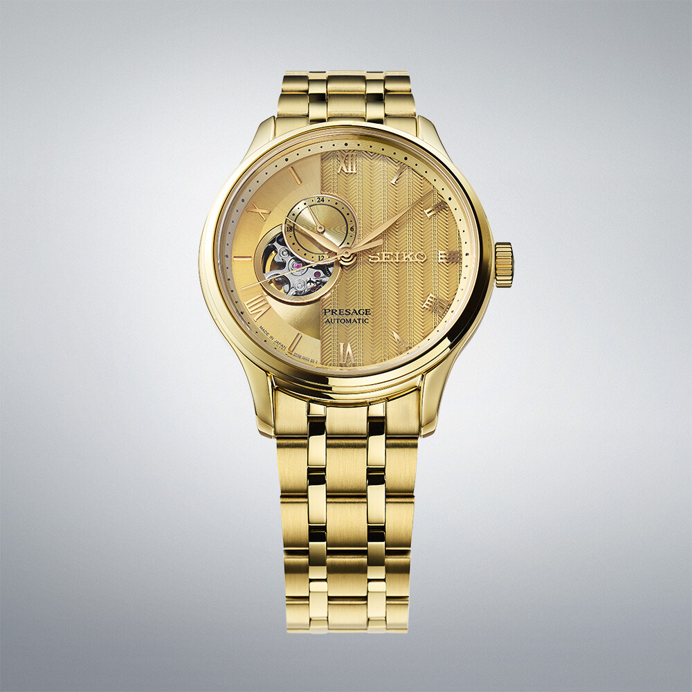 Eine goldene Herrenuhr mit einem goldenen Armband und einem Zifferblatt mit einem offenen Herz und vertikalen Rillen.