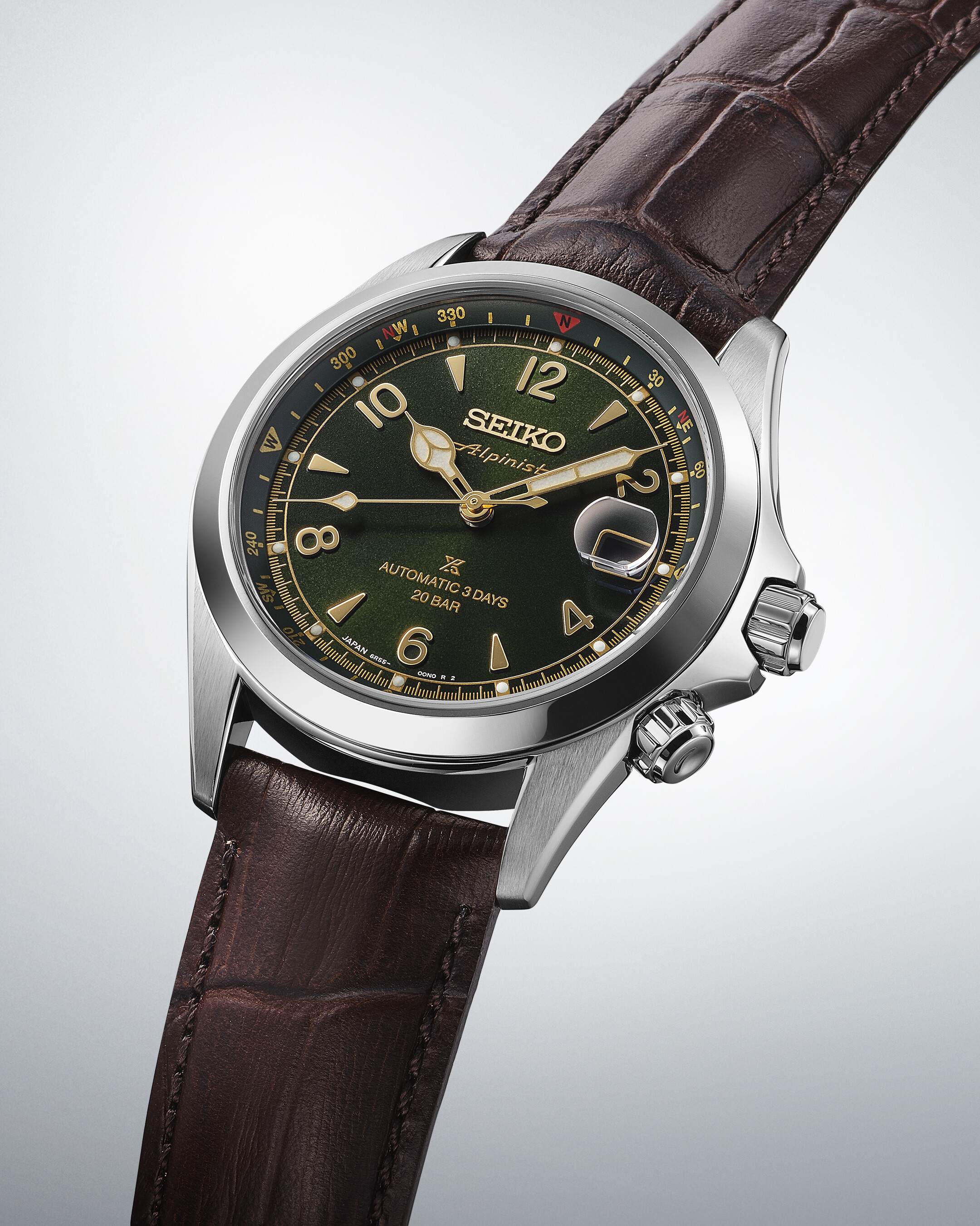 Eine silberne Uhr mit einem dunkelgrünen Zifferblatt, goldenen Zeigern und braunem Lederarmband.