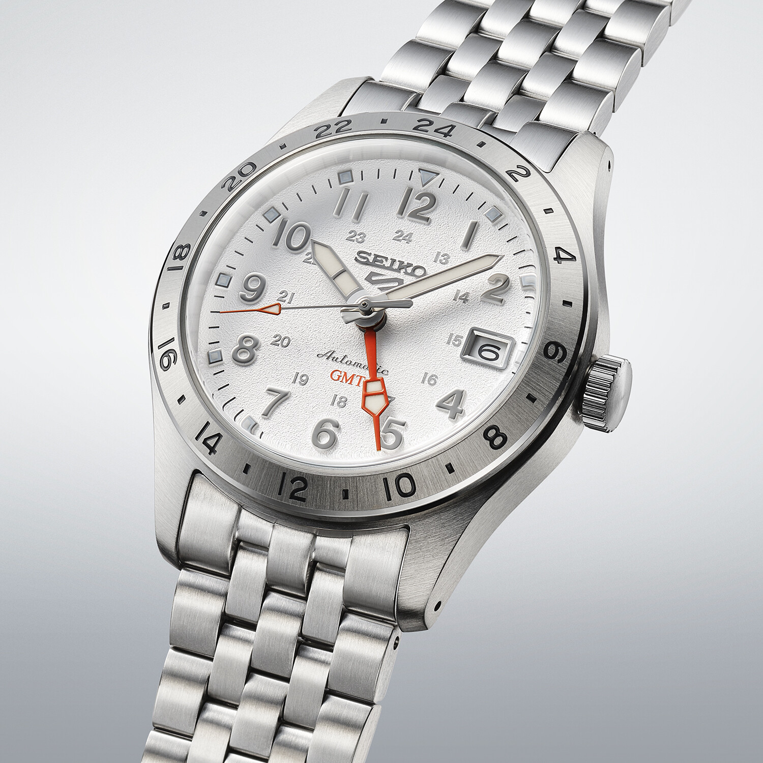 Eine silberne Herrenarmbanduhr mit weißem Zifferblatt und roten GMT-Zeigern. Das Armband ist aus Silber.
