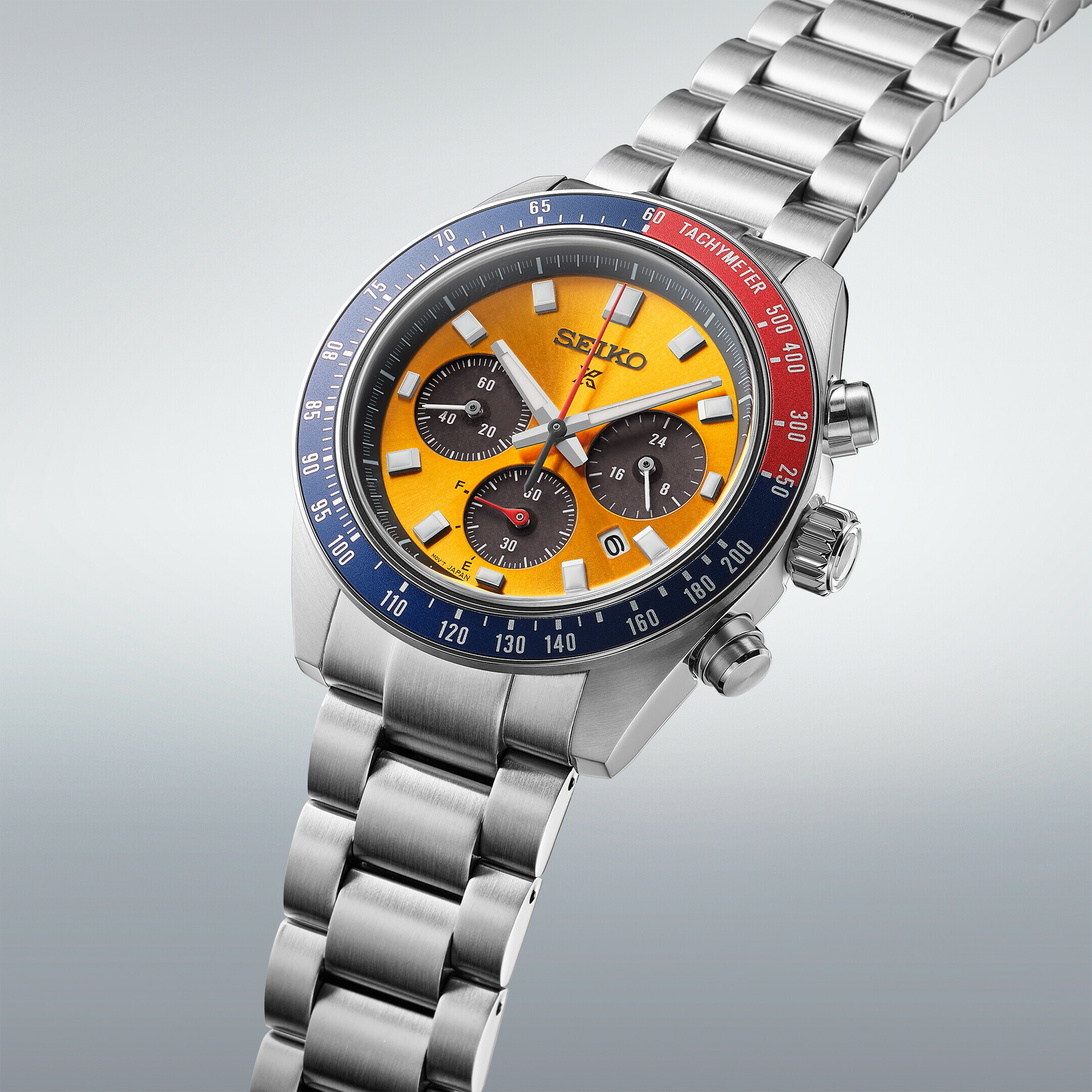 Eine silberne Armbanduhr mit einem gelben Zifferblatt und einer blauen und roten Lünette.