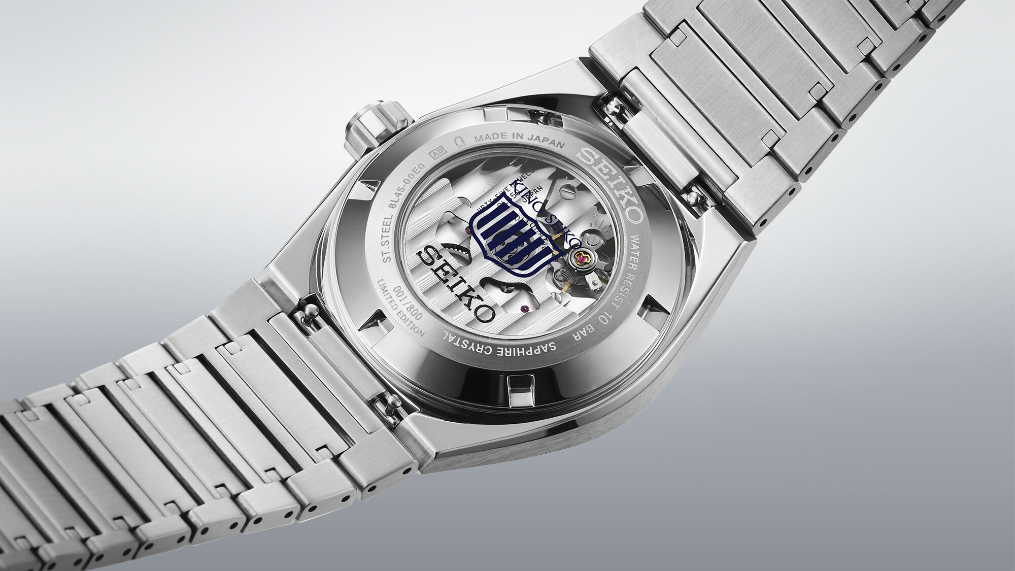 Ein silbernes Herrenarmbanduhr-Gehäuse mit Rückseite zeigt ein silbernes mechanisches Werk mit blau-weißen Akzenten.