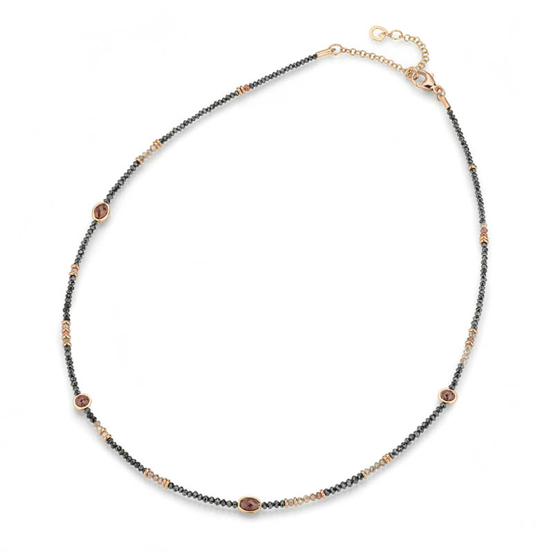 Ein feingliedriges Collier mit kleinen dunklen und helleren Perlen sowie einigen ovalen, bernsteinfarbenen Schmucksteinen.