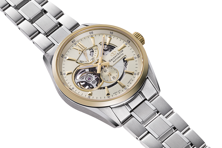 Eine elegante Armbanduhr mit einem cremefarbenen Zifferblatt, goldfarbenen Akzenten und einem silbernen Armband.