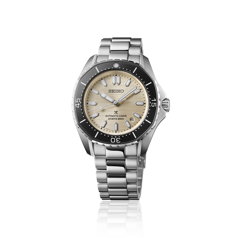 Eine silberne Armbanduhr mit beigem Zifferblatt und schwarzer Lünette