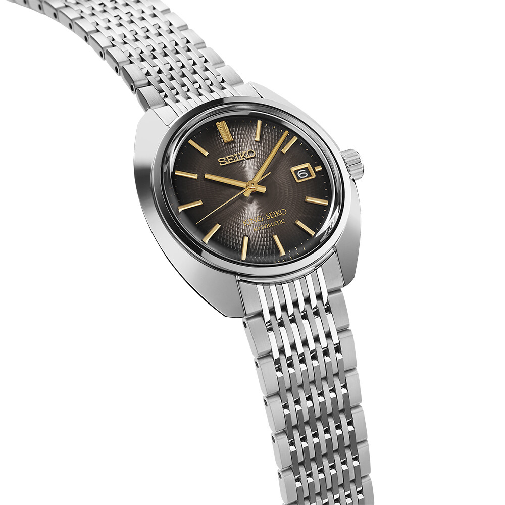 Armbanduhr mit dunklem, texturiertem Zifferblatt und goldenen Zeigern auf einem schmalen Metallarmband.