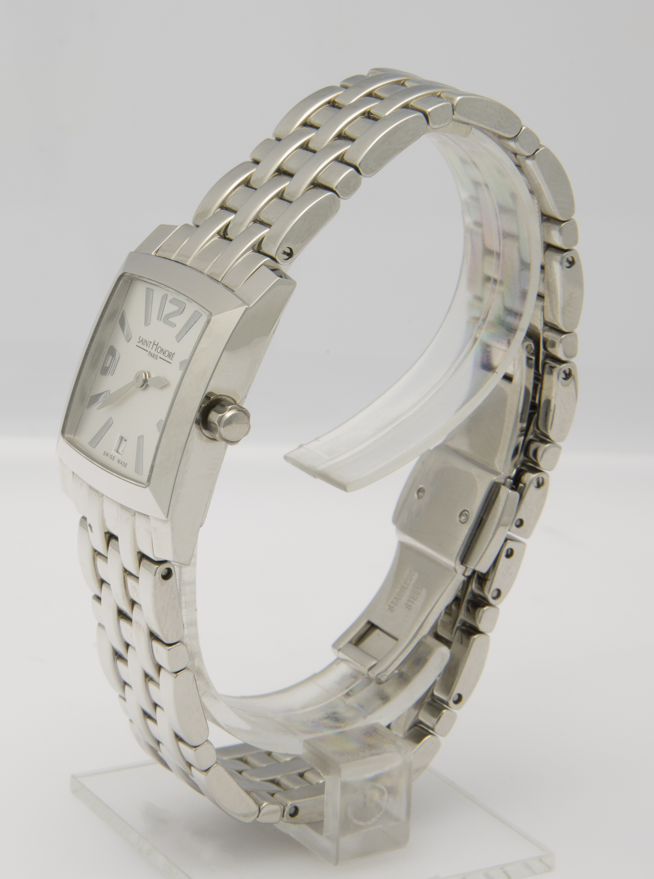 Eine silberne Damenuhr mit rechteckigem Zifferblatt und silbernem Gliederarmband wird auf einem transparenten Ständer präsentiert.
