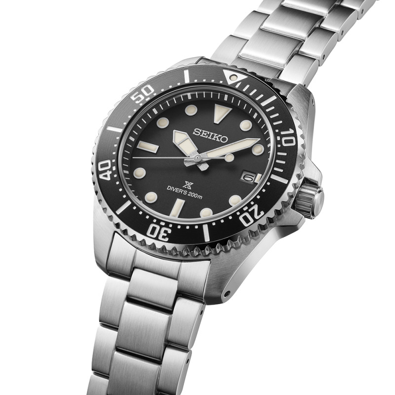 Eine silberne Armbanduhr mit schwarzem Zifferblatt und leuchtenden Zeigern, die über eine Keramikeinfassung verfügt.
