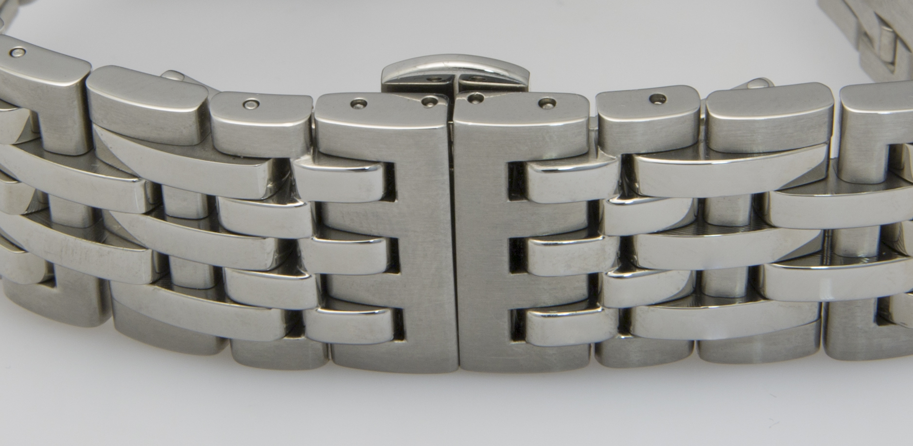 Ein poliertes, silbernes Armband einer Uhr mit einem eleganten Verschluss und beweglichen Gliedern.