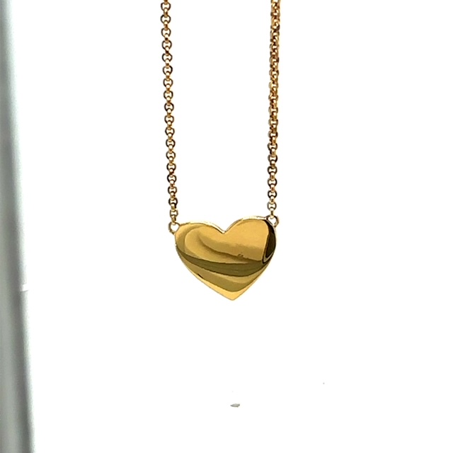 Ein goldenes Herzanhänger an einer feinen Gliederkette, das eine glatte, polierte Oberfläche aufweist.