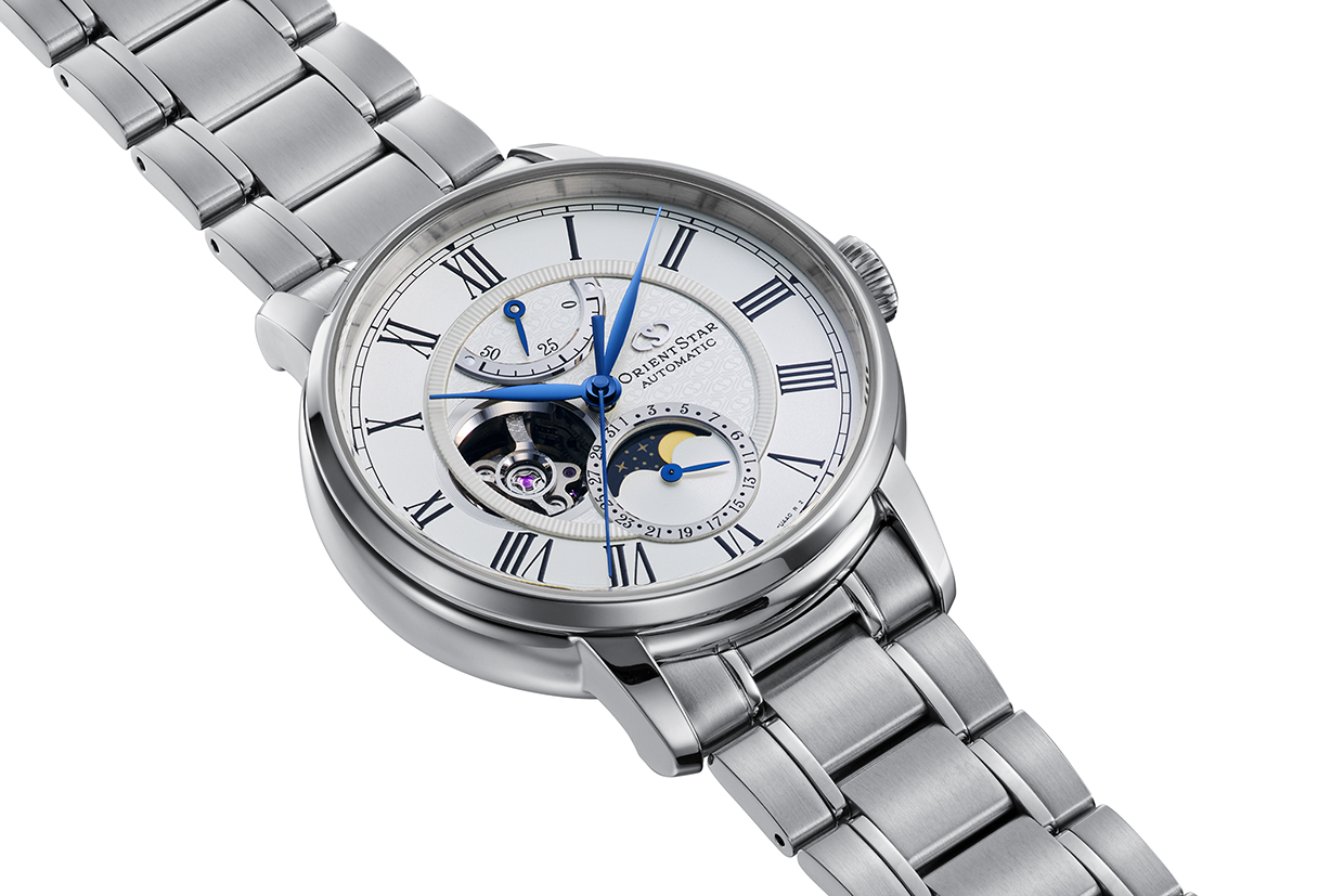 Eine silberne Armbanduhr mit weißem Zifferblatt, blauen Zeigern und römischen Ziffern. Sie hat ein sichtbares Uhrwerk.